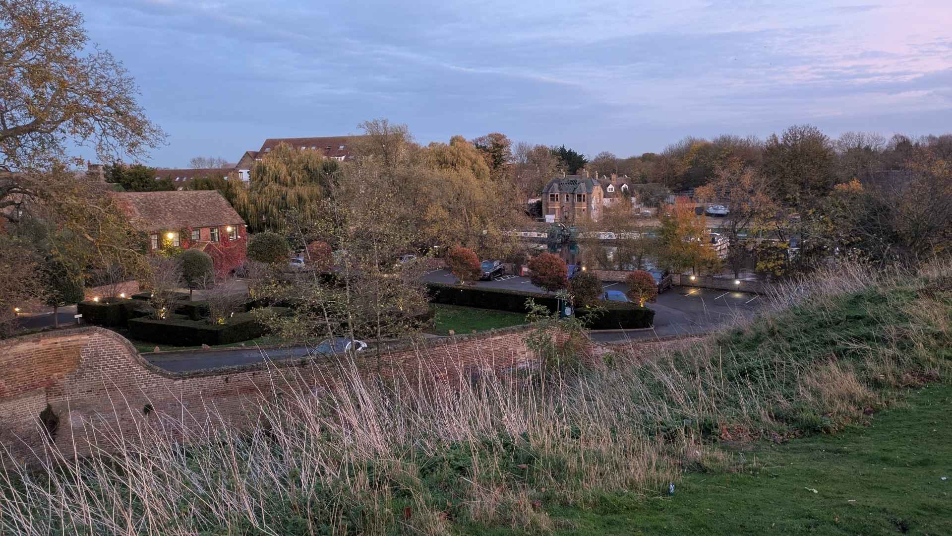 Huntingdon at dusk seen from the old castle hill — willows over the Ouse, pubs and houses in pink evening light